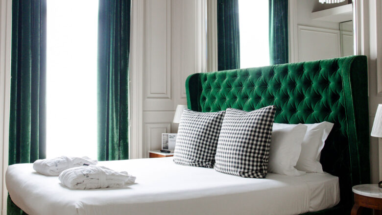 Dettaglio di uno dei letti delle camere dal Matilde Boutique Hotel, con struttura imbottita verde.