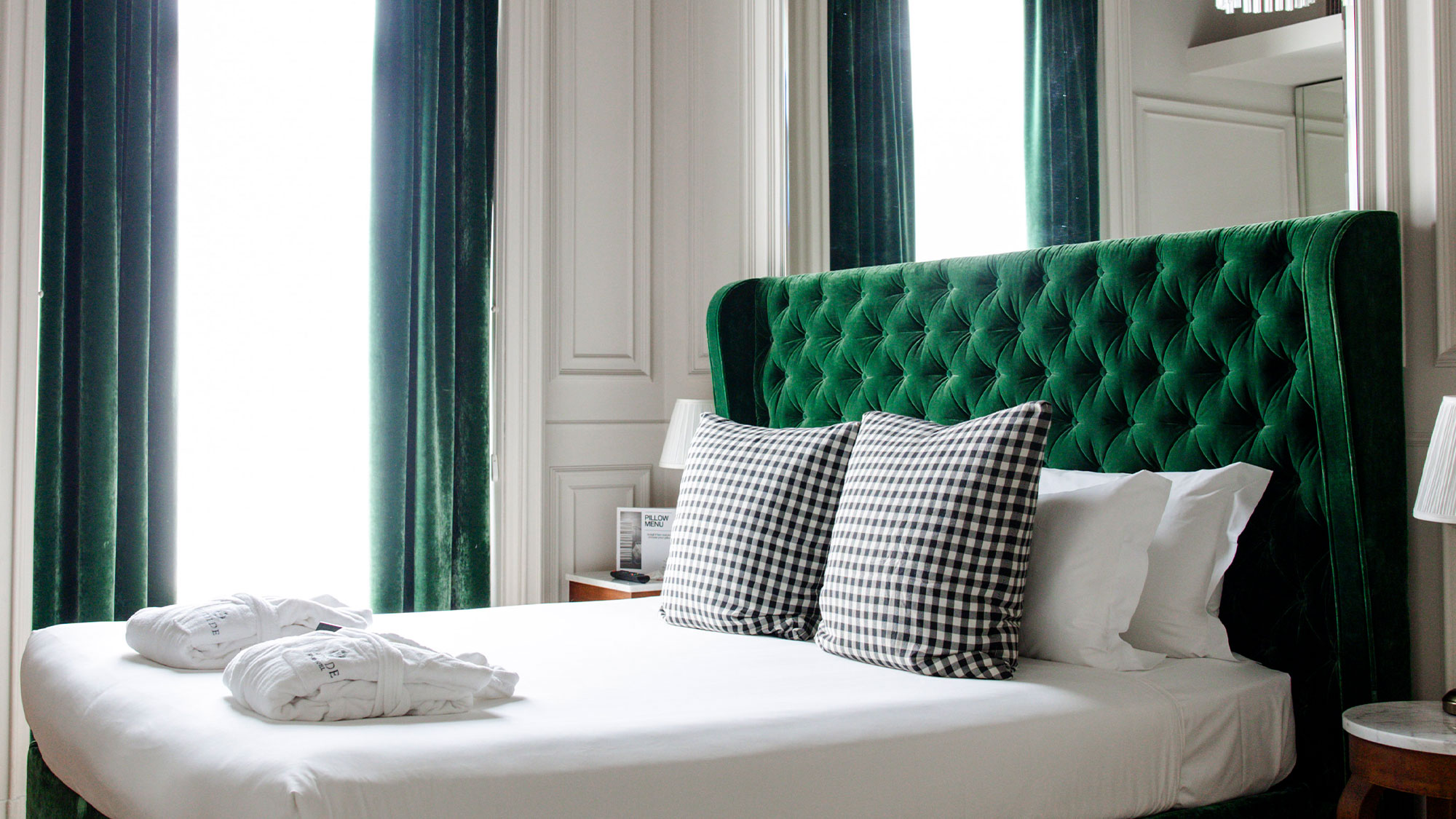 Dettaglio di uno dei letti delle camere dal Matilde Boutique Hotel, con struttura imbottita verde.