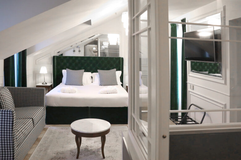 Foto di dettaglio di una delle camere del Matilde Boutique Hotel, con un divano con tessuto a scacchi e letto matrimoniale con struttura imbottita verde
