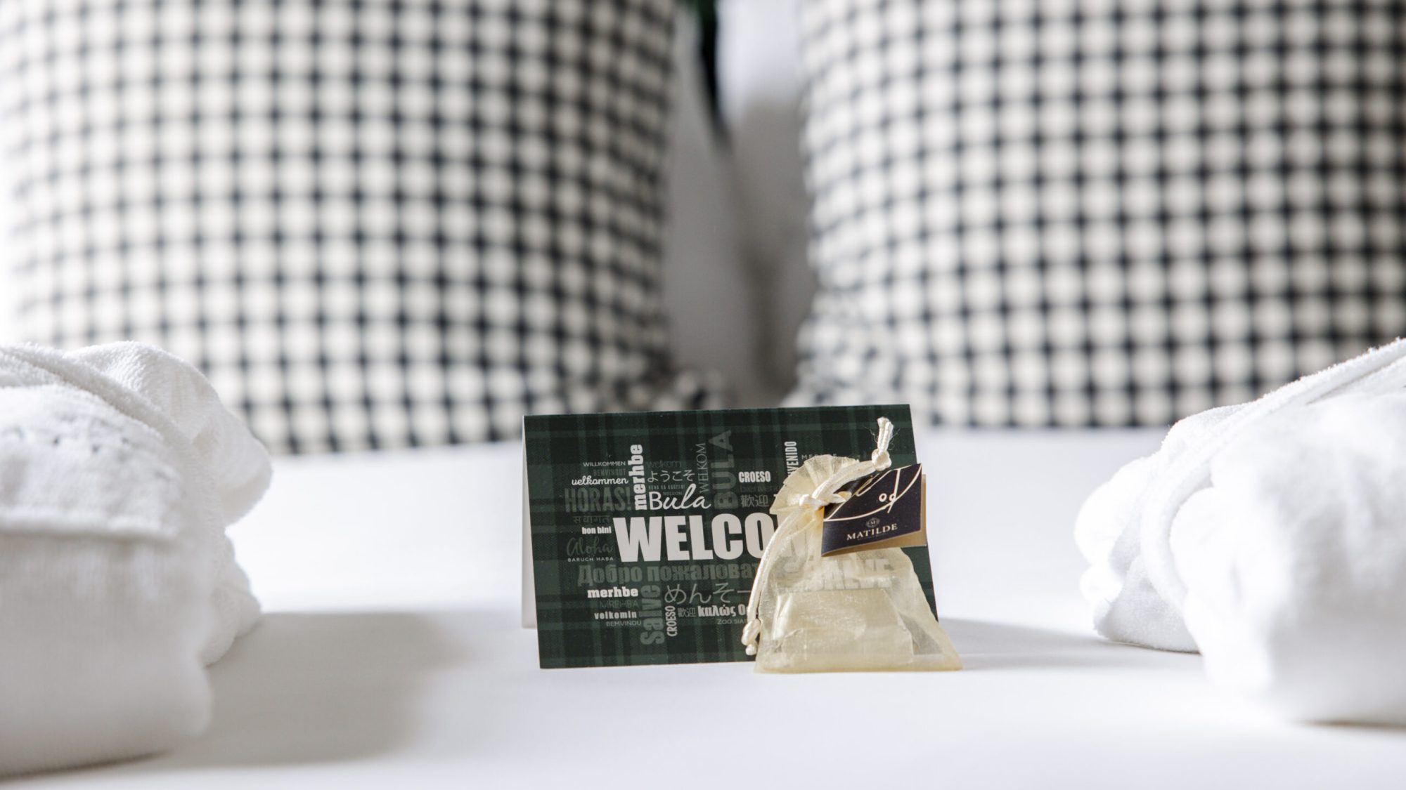 Foto di dettaglio di un letto matrimoniale del Matilde Boutique Hotel, con un piccolo omaggio ed un biglietto di benvenuto.