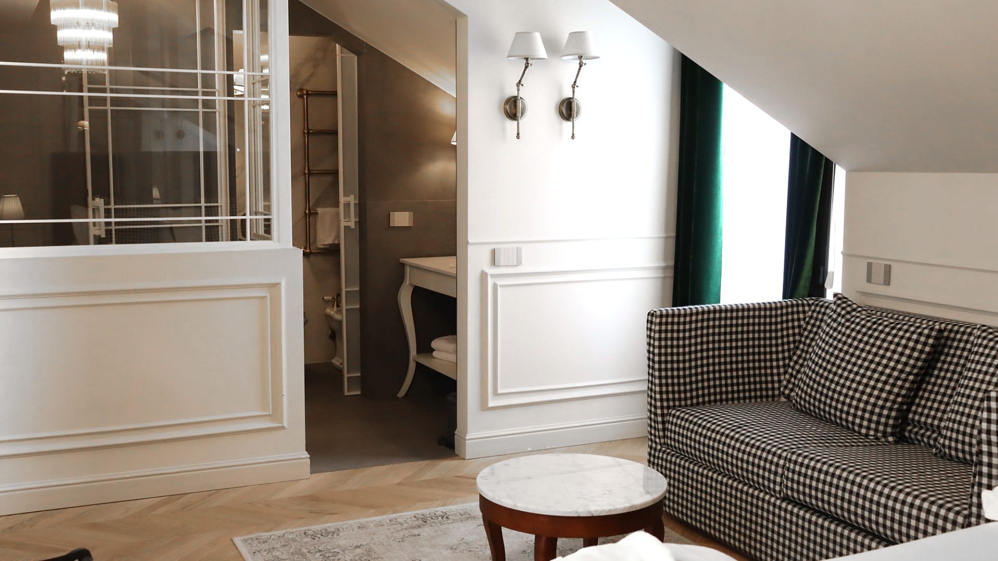 Foto di dettaglio di una delle camere del Matilde Boutique Hotel, con un divano con tessuto a scacchi, tavolino elegante e zona bagno