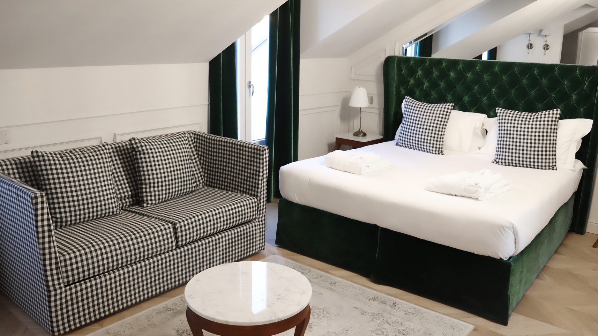 Foto di dettaglio di una delle camere del Matilde Boutique Hotel, con un divano con tessuto a scacchi e letto matrimoniale con struttura imbottita verde