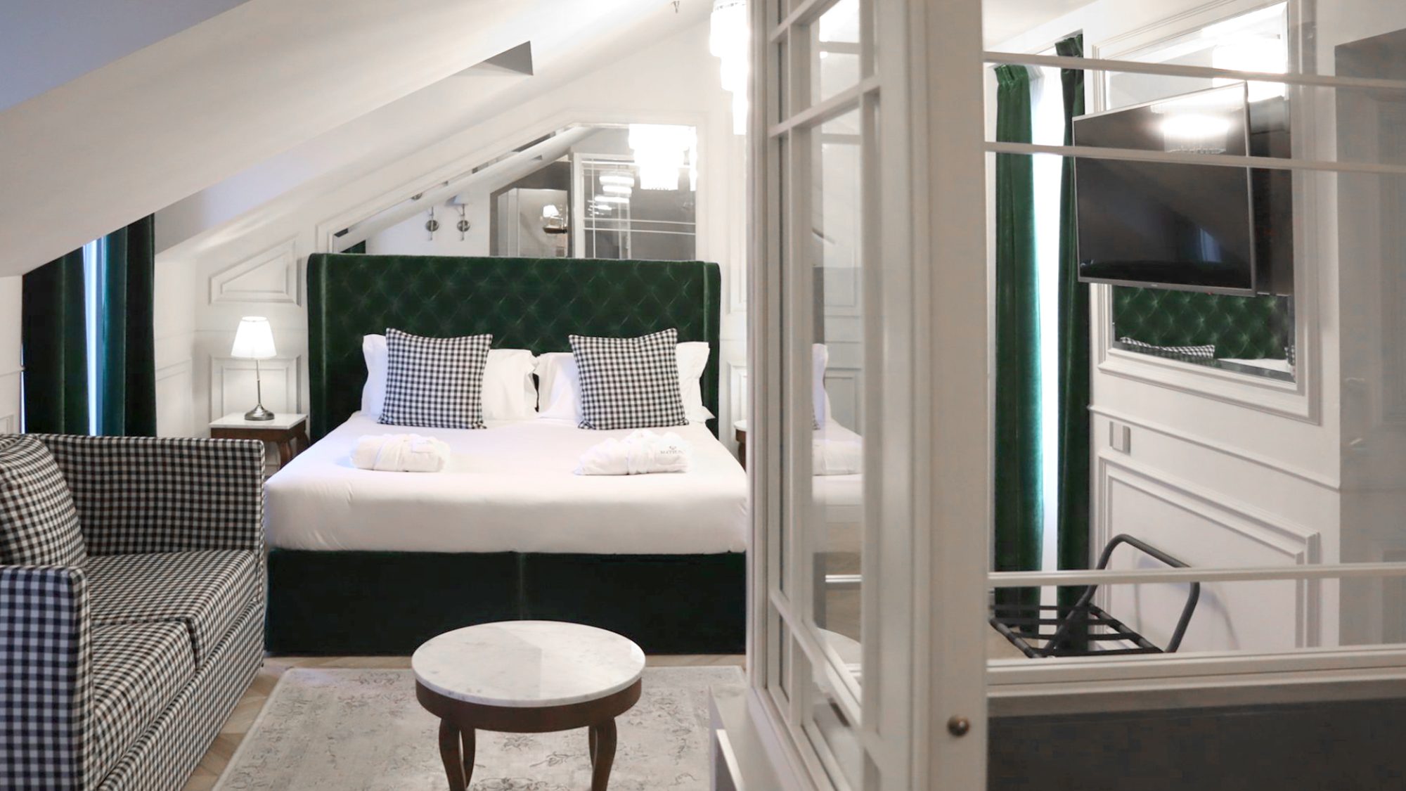 Foto di dettaglio di una delle camere del Matilde Boutique Hotel, con un divano con tessuto a scacchi e letto matrimoniale con struttura imbottita verde